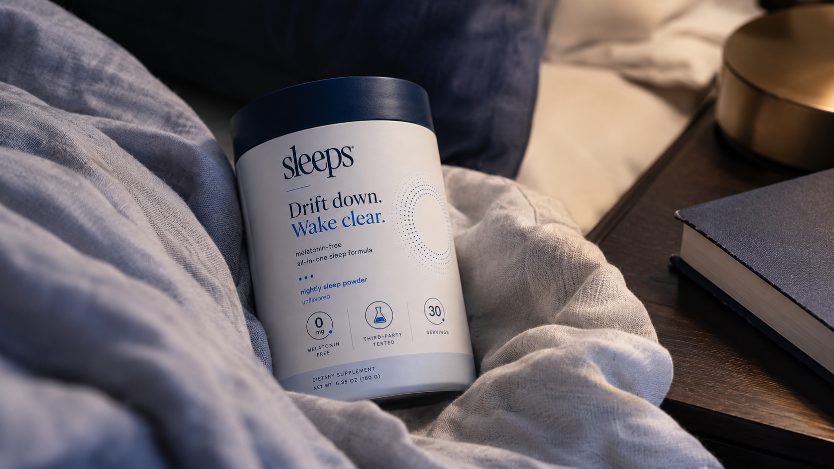Container of 'sleeps' product on a bed with a blurred background